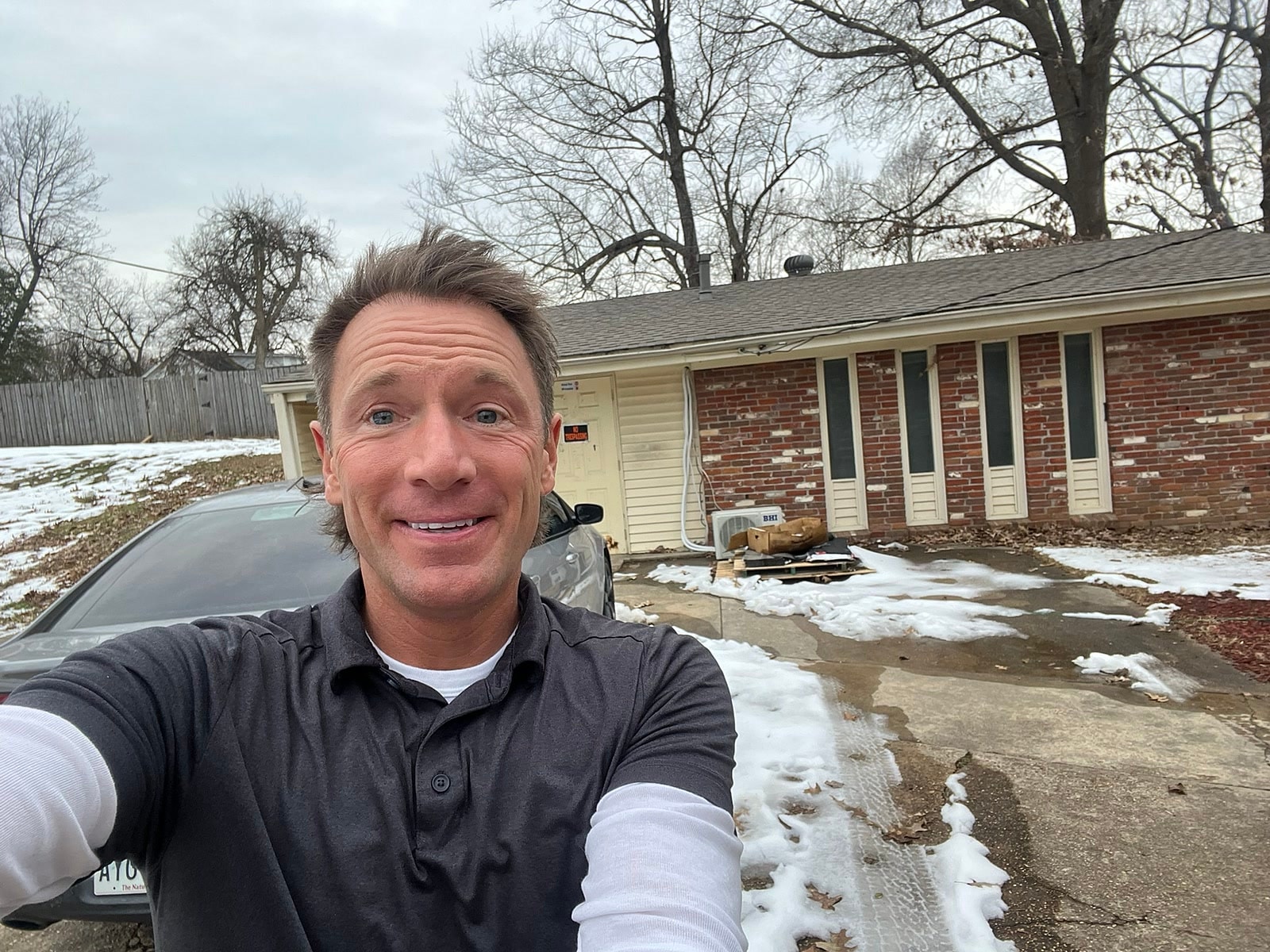 Rusty on-site in front of a beige and brick ranch house